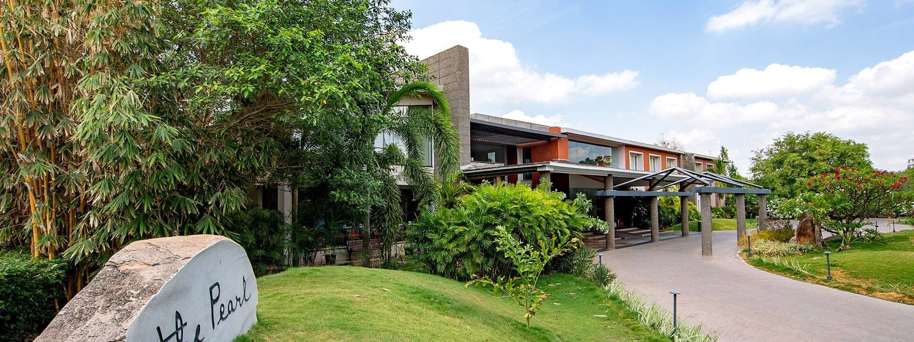 The approach to The Pearl, the hotel's name cut into a boulder on the lawn and the building behind.