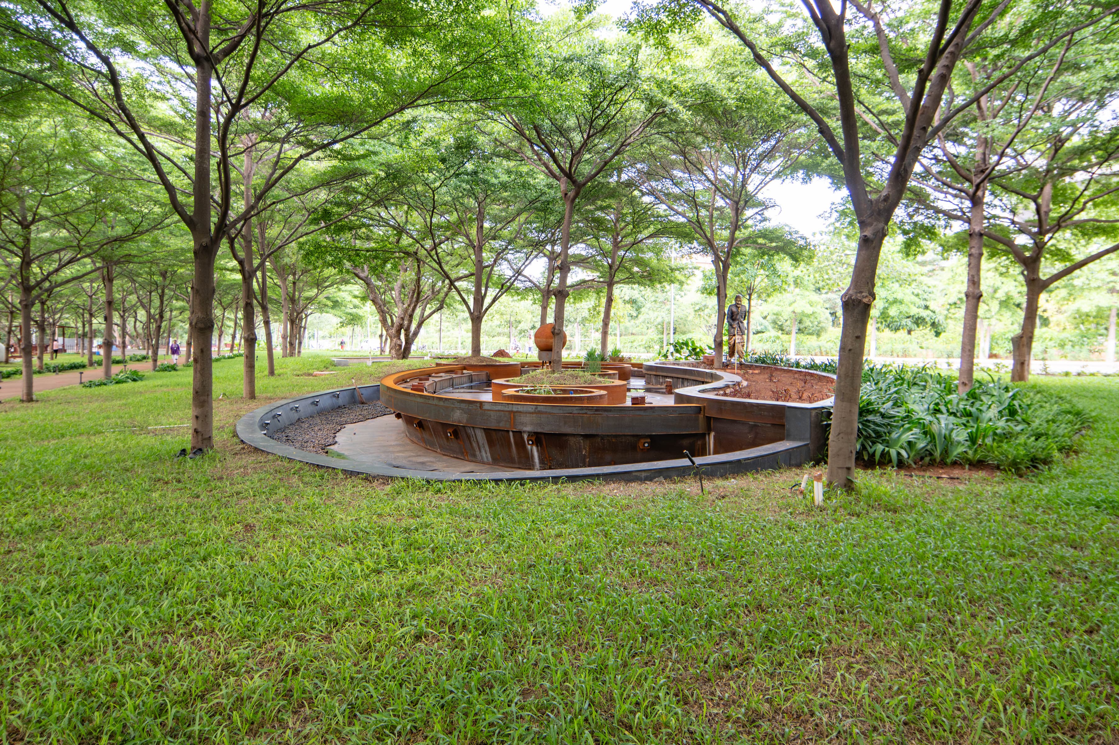 An avenue of trees at Babuji Vanam beside a long stepped water channel.
