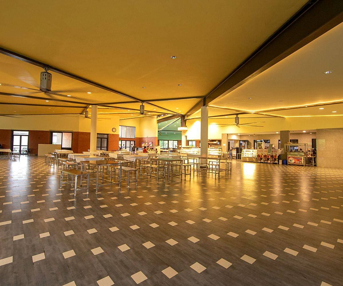 The campus dining hall at Kanha, a wide timber-ceilinged room of empty tables between sittings.