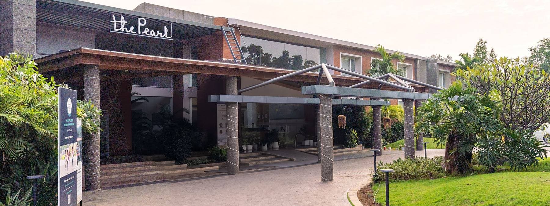 The entrance canopy at The Pearl, the hotel's name above the doors and planting either side.