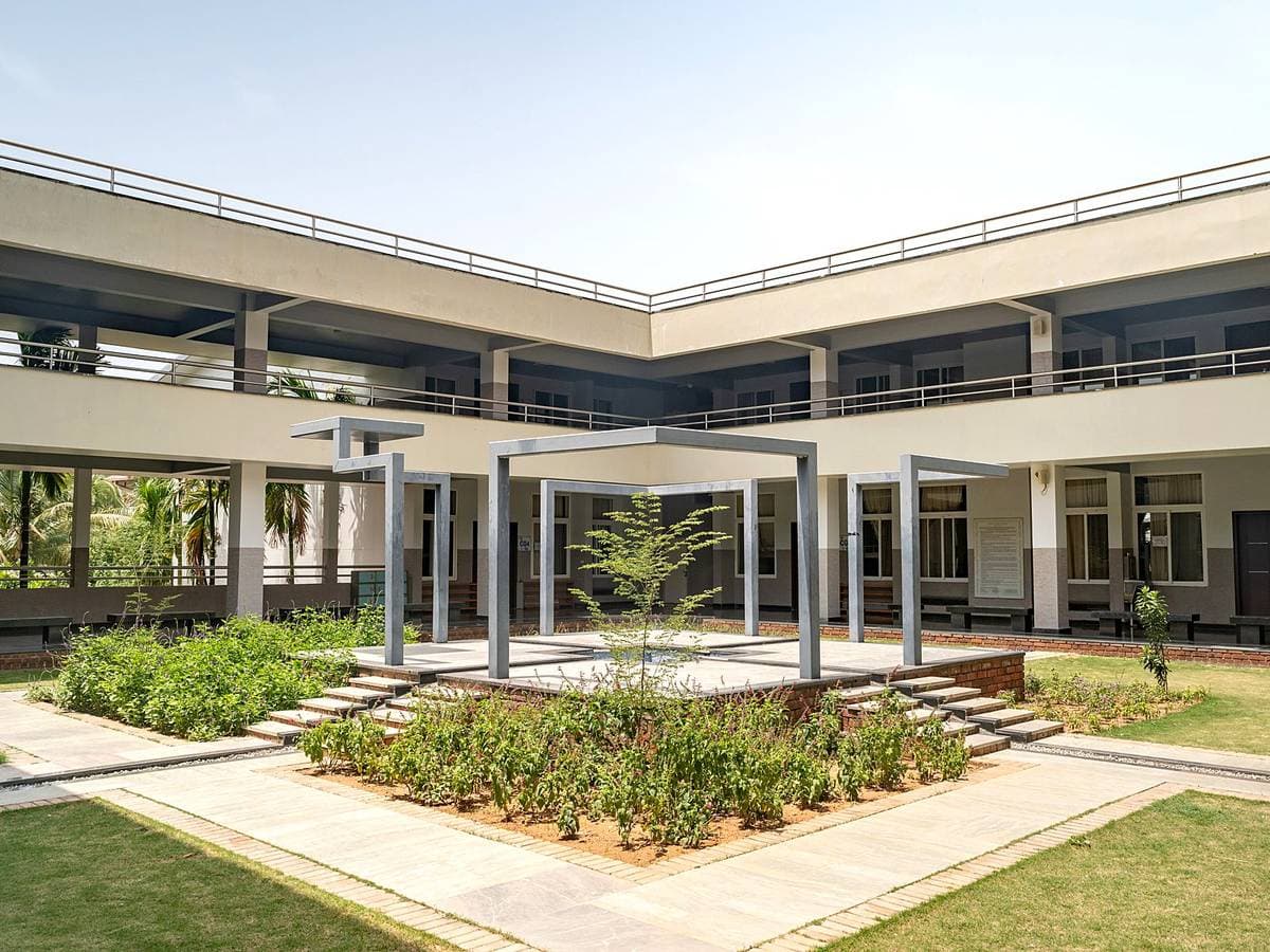 A two-storey courtyard building at Kanha, its colonnade opening onto lawn and planting.